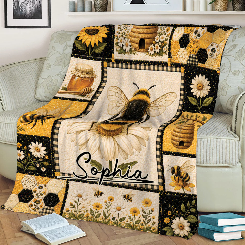 Close view of bee throw blanket on a sofa with floral, honeycomb and beehive illustrations