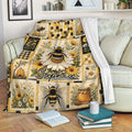 Bee blanket draped over a sofa with floral panels, honeycomb details, beehives, and honey jar artwork
