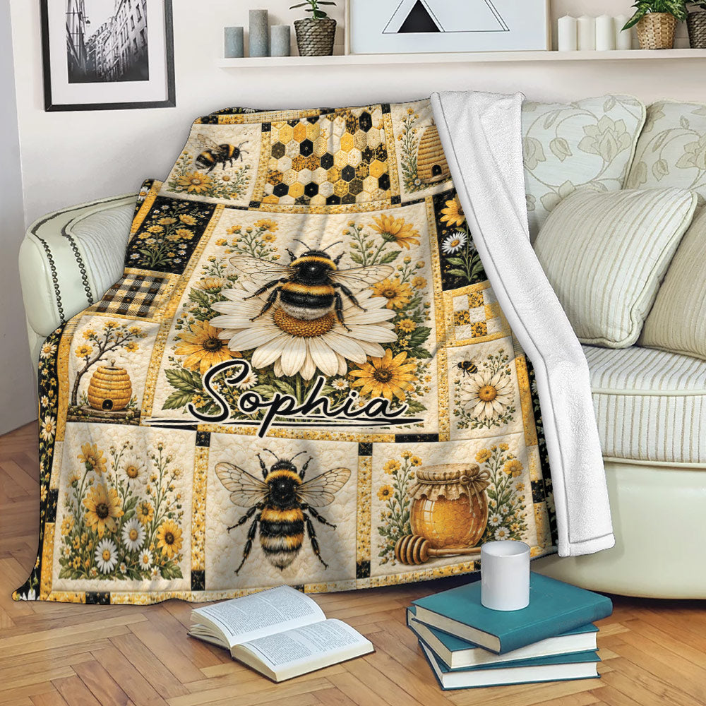 Bee blanket draped over a sofa with floral panels, honeycomb details, beehives, and honey jar artwork