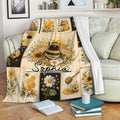Honeybee blanket draped over a sofa, featuring floral panels, honey jars, beehives, and warm golden tones