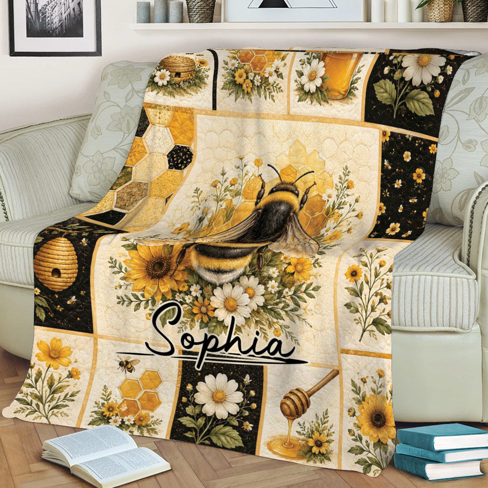 Bee blanket displayed on a couch with honeycomb, sunflowers, daisies, honey dipper, and botanical artwork