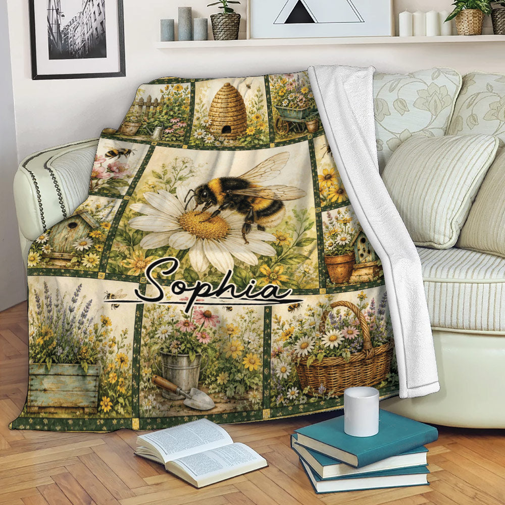 Bee throw blanket draped over a sofa, featuring bumblebee artwork, flowers, a beehive, and colorful garden scenes