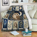 Owl throw blanket draped over a sofa with moon, stars, leafy branches, and woodland-inspired artwork