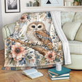 Floral owl blanket draped over a sofa with an illustrated woodland design