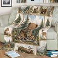Close view of a bear throw blanket on a couch featuring woodland scenery, deer, trees, and mountain artwork