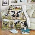 Cow blanket displayed on a sofa with Holstein cow artwork, farmhouse scenes, daisies, and a barn