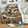 Cow throw blanket draped over a sofa with sunflower farm artwork and black and white cattle scenes