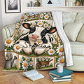 Cow calf throw blanket with daisy artwork draped across a cozy sofa in a bright living room