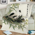Close view of a panda throw blanket displayed on a sofa with detailed bamboo foliage