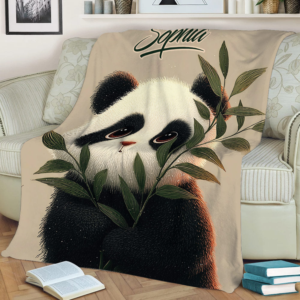 Close lifestyle view of a panda throw blanket with leafy bamboo artwork on a sofa