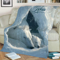 Close view of polar bear family artwork on a blue Arctic throw blanket across a living room sofa
