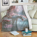 Pastel unicorn blanket draped over a sofa, showing a magical forest, waterfall, rainbow, and lake scene