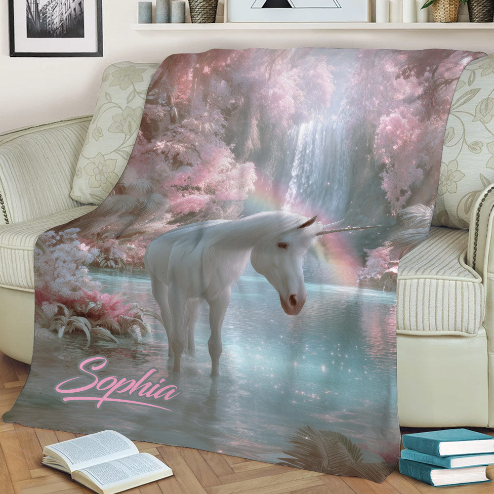 Unicorn throw blanket displayed on a sofa with dreamy pink trees, sparkling water, waterfall, and rainbow
