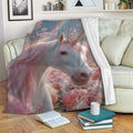 Unicorn blanket draped across a sofa with a pastel fantasy scene, pink mane, rainbow, butterflies, and flowers