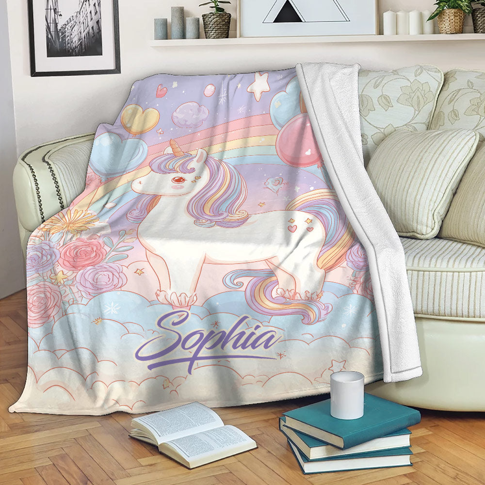 Pastel unicorn blanket draped over a sofa with rainbows, balloons, flowers, and dreamy cloud artwork