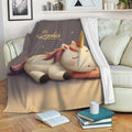 Cozy unicorn throw blanket draped over a sofa with a sleeping unicorn and starry artwork