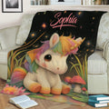Whimsical unicorn blanket displayed on a sofa with rainbow mane, glowing stars, flowers, and mushrooms