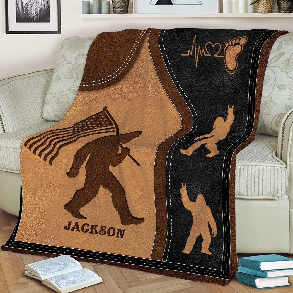 Close view of a rustic Bigfoot throw blanket with flag design on a sofa