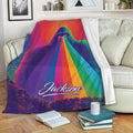 Bigfoot throw blanket draped over a couch with vivid rainbow artwork and forest scenery