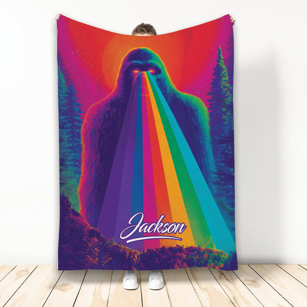 Bigfoot blanket with colorful rainbow beams, glowing eyes, and a dark evergreen forest design