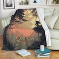 Bigfoot blanket draped over a sofa with a silhouetted Sasquatch in a misty evergreen forest