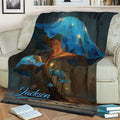 Close view of a mushroom throw blanket featuring glowing blue caps and woodland scenery