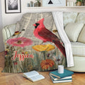 Cardinal blanket draped across a sofa with red bird, flowers, and vintage botanical artwork
