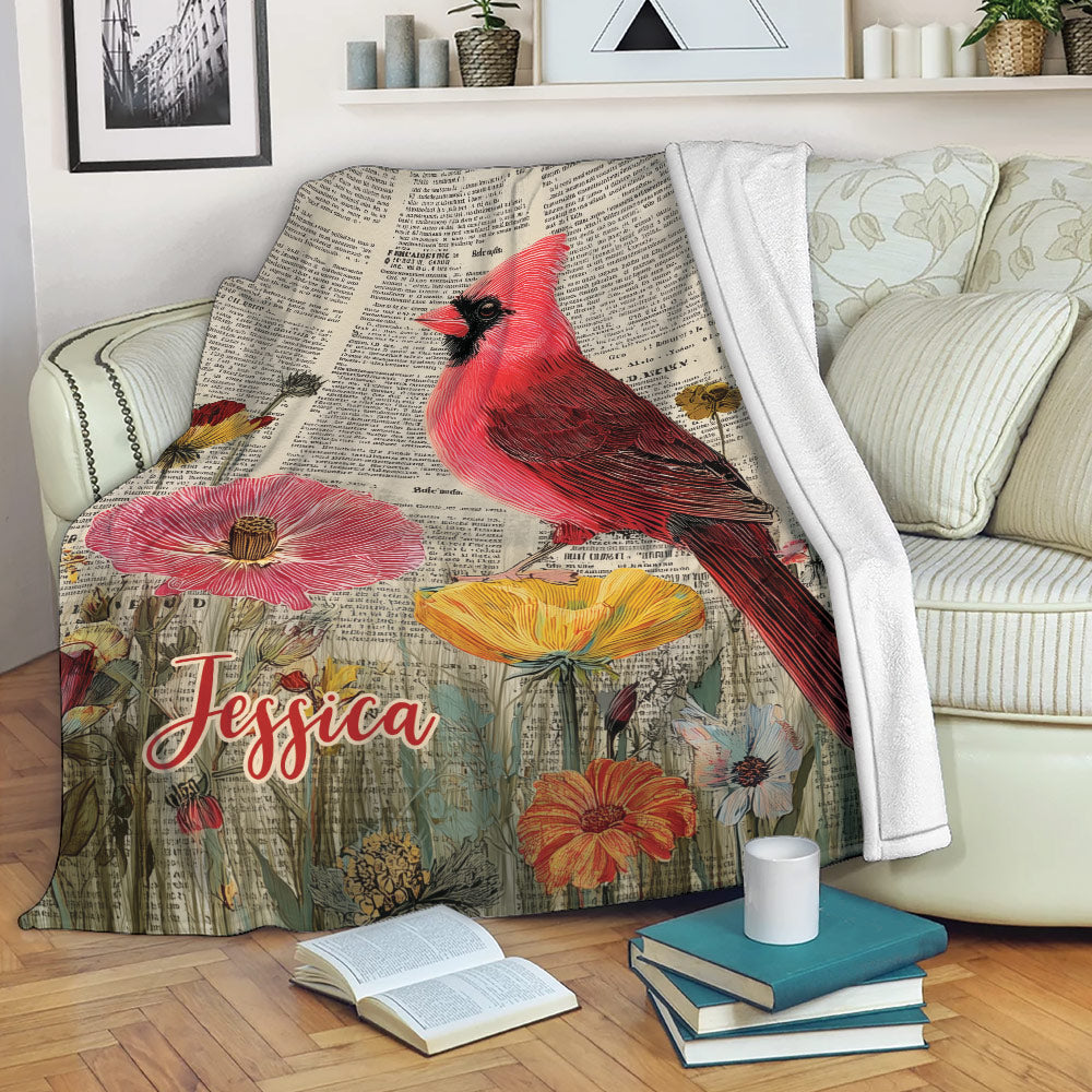 Cardinal blanket draped across a sofa with red bird, flowers, and vintage botanical artwork