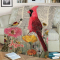 Close view of a cardinal throw blanket featuring a red bird, floral design, and antique-inspired backdrop