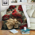 Cardinal throw blanket displayed on a sofa with poinsettias, pinecones, berries, and cozy reading decor