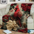 Red cardinal blanket draped over a sofa with holiday flowers, evergreen branches, pinecones, and berries
