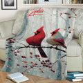 Winter cardinal throw blanket displayed on a sofa with two birds resting on a berry-covered branch