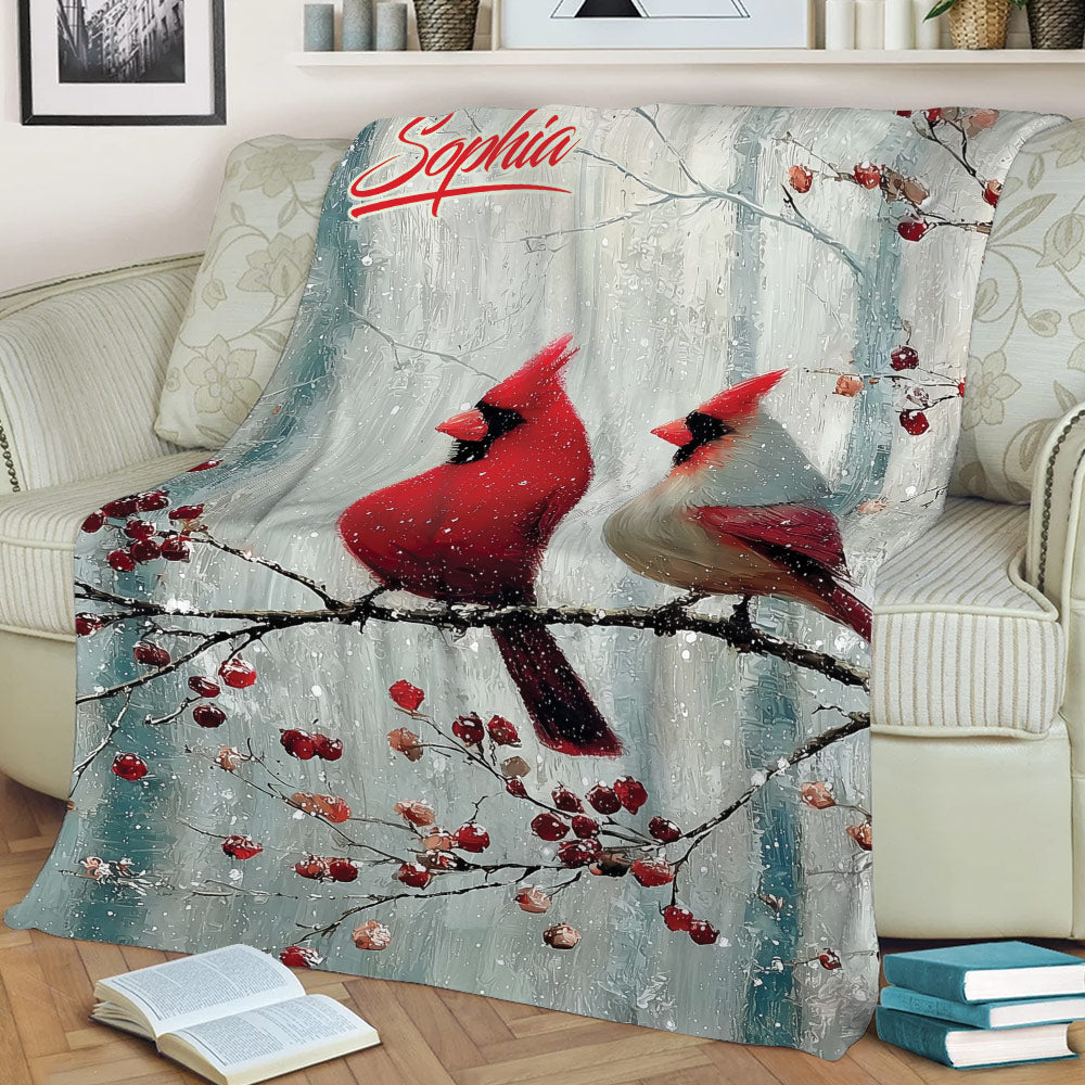 Winter cardinal throw blanket displayed on a sofa with two birds resting on a berry-covered branch