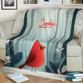 Red cardinal throw blanket displayed on a sofa with snowy woodland artwork and muted blue botanical accents