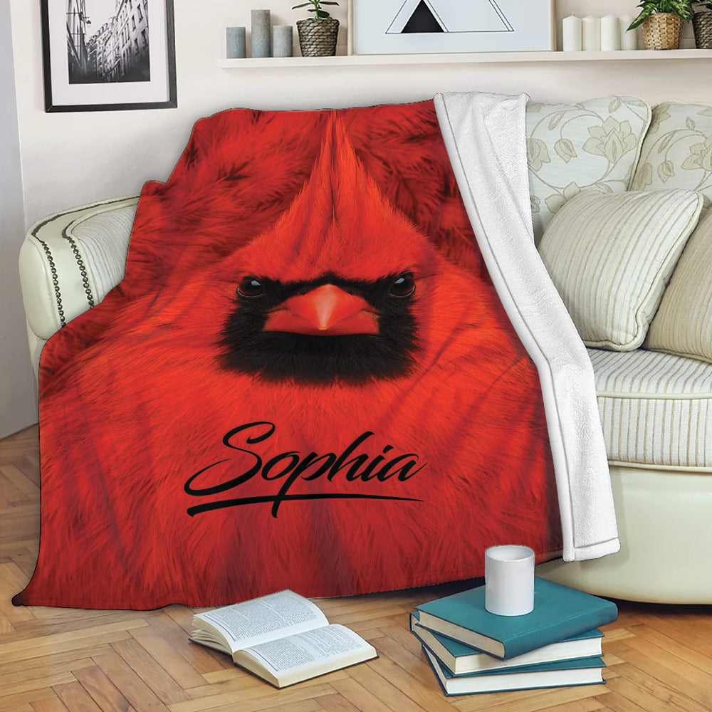 Red cardinal blanket draped across a sofa with bold bird artwork and cozy reading decor