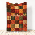 Thanksgiving throw blanket with warm autumn plaid patchwork artwork displayed against a light wall