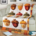 Close view of an autumn Thanksgiving blanket featuring colorful acorns, leaves, pumpkins, and patchwork details