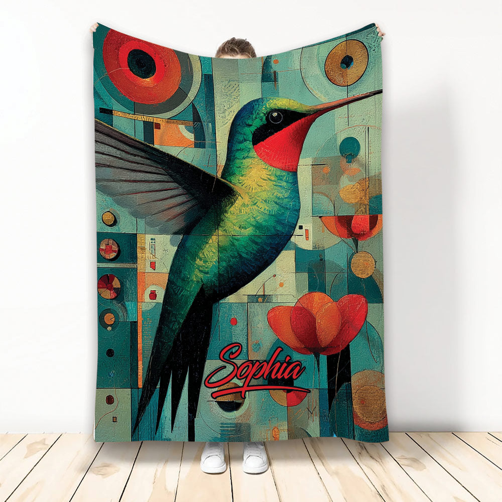 Colorful hummingbird blanket with geometric artwork and red flowers shown hanging in a room