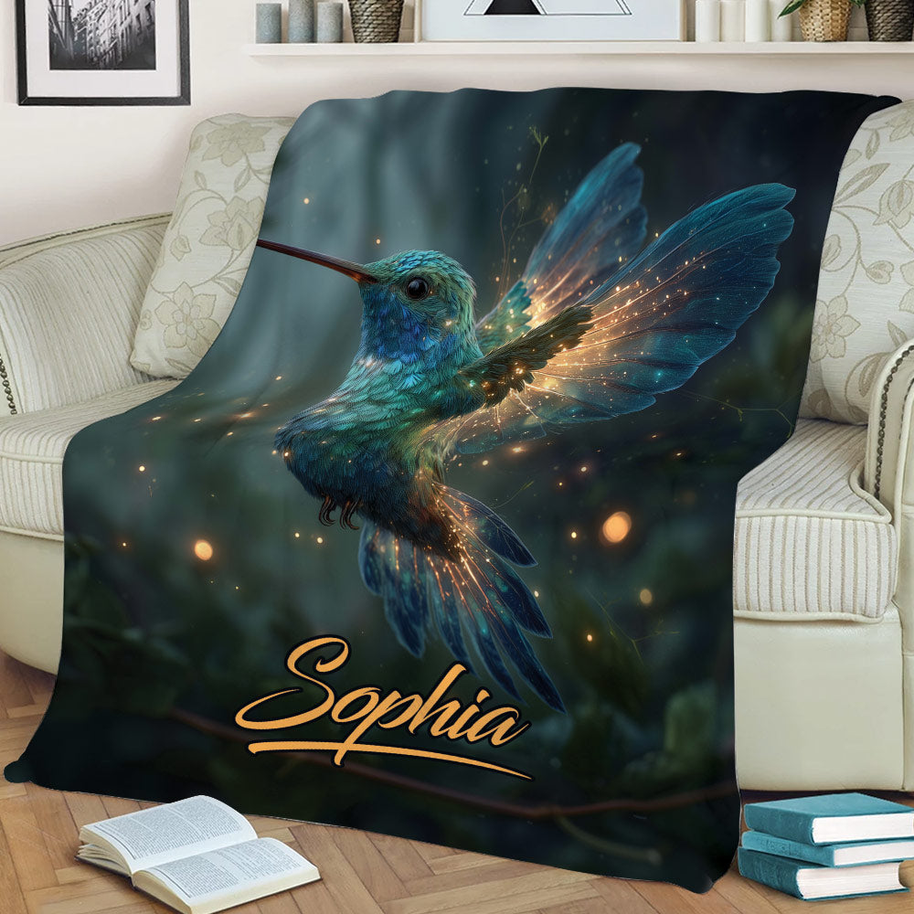 Hummingbird throw blanket displayed on a sofa with glowing woodland artwork