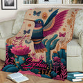 Detailed hummingbird blanket displayed on a sofa with colorful floral and cactus artwork