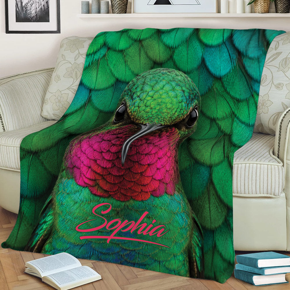Close view of vibrant hummingbird artwork on a blanket styled across a sofa