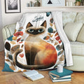 Siamese cat blanket draped over a sofa in a cozy living room with books