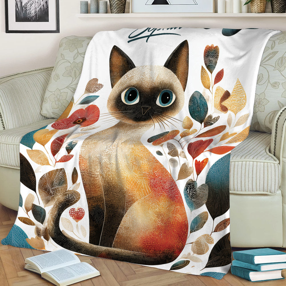 Close view of Siamese cat artwork on a botanical throw blanket over a sofa