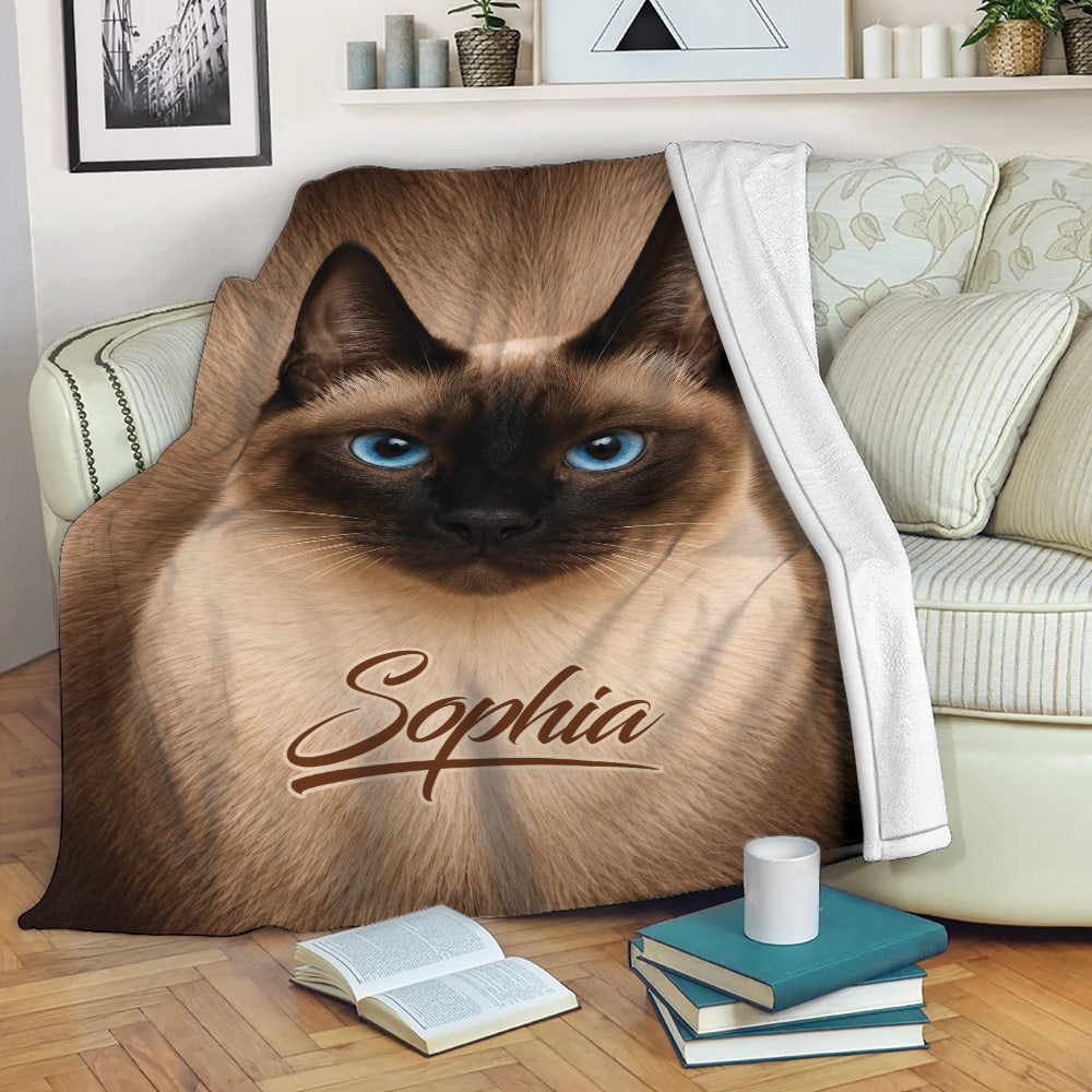 Siamese cat blanket draped over a sofa, showcasing blue eyes and detailed brown fur artwork