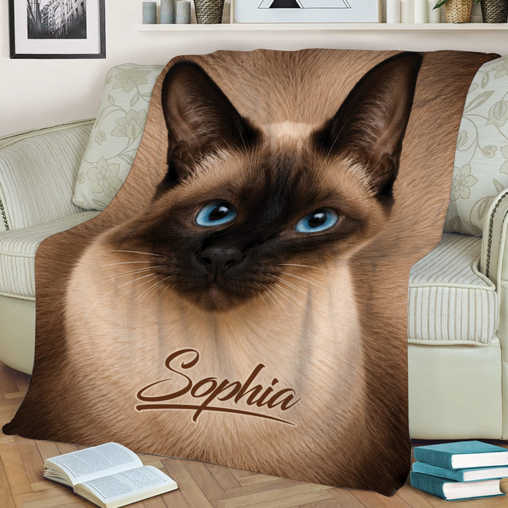 Close-up Siamese cat throw blanket displayed on a sofa with distinctive dark markings and blue eyes