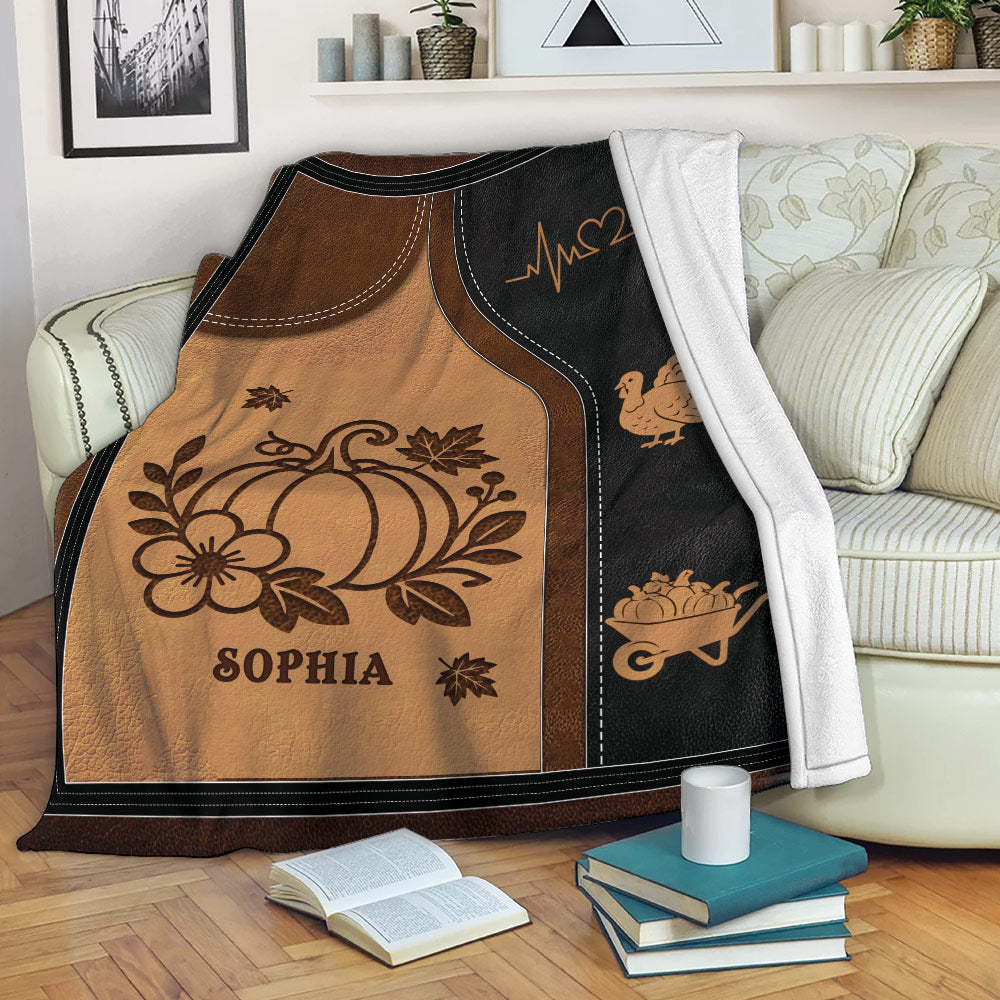 Autumn pumpkin throw blanket draped over a sofa with harvest and turkey artwork in warm earthy colors