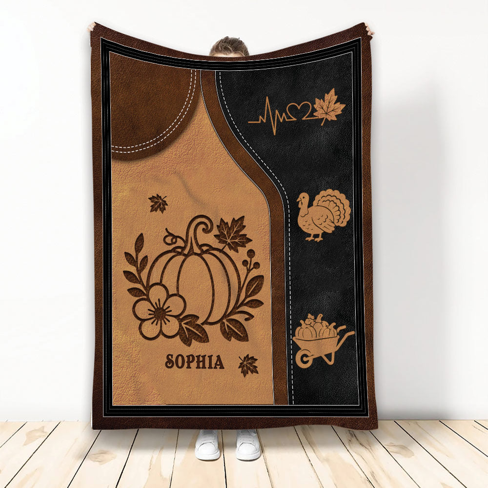 Autumn throw blanket with pumpkin, turkey, harvest wheelbarrow, maple leaves, and warm brown artwork