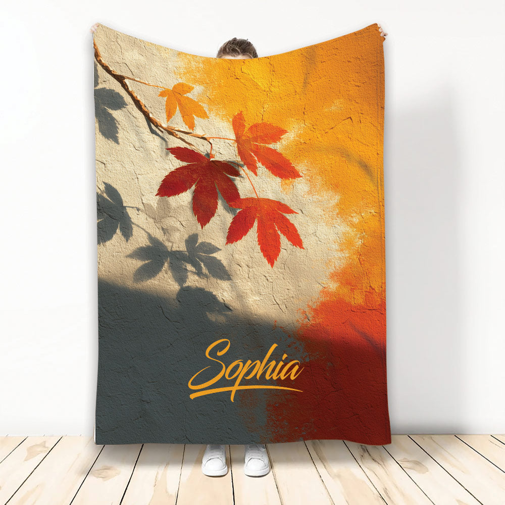 Autumn leaf throw blanket displayed upright with warm orange, red, gold and charcoal fall artwork