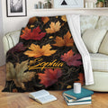 Autumn foliage throw blanket draped over a sofa with warm red, orange, gold, and burgundy leaves
