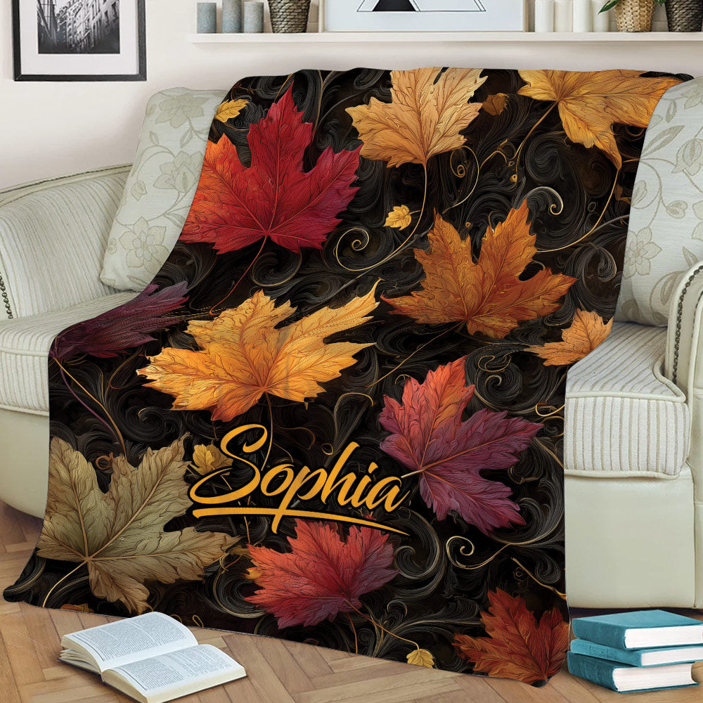 Fall leaves blanket displayed on a couch with rich autumn colors and decorative swirling details